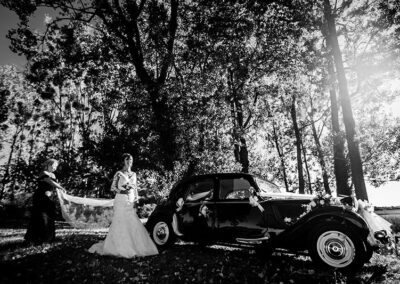 Portrait en noir et blanc d'une mariée devant une voiture