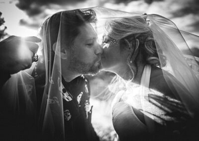 Photo de mariage - un couple s'embrasse, enveloppé dans le voile de la mariée